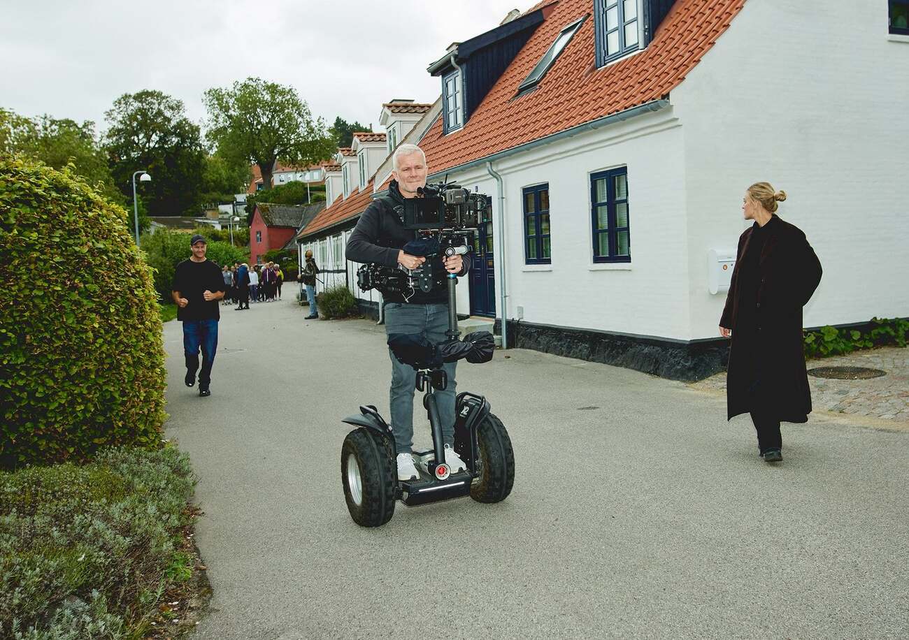 Steadicam operator rolling through a Danish residential street ahead of a group of runners, from the shoot for a bank client's campaign
